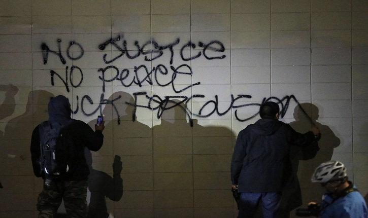 Demonstrators spray words on a wall during a demonstration following the grand jury decision in the Ferguson, Missouri shooting of Michael Brown, in Oakland